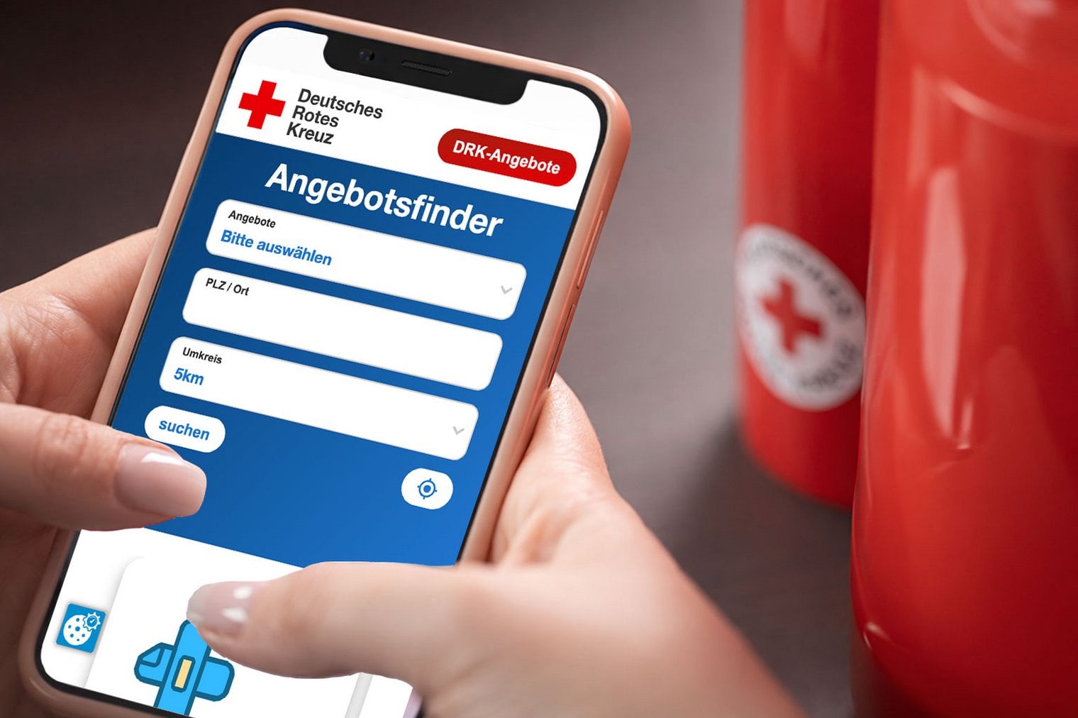 Dieses Imagebild zeigt eine Hand die ein Smartphone hält. Auf dem Smartphone ist die Suchmaske von DRK-Angebote geöffnet.